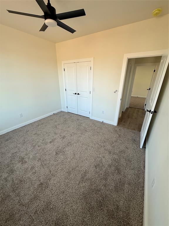 unfurnished bedroom featuring ceiling fan, carpet, and a closet