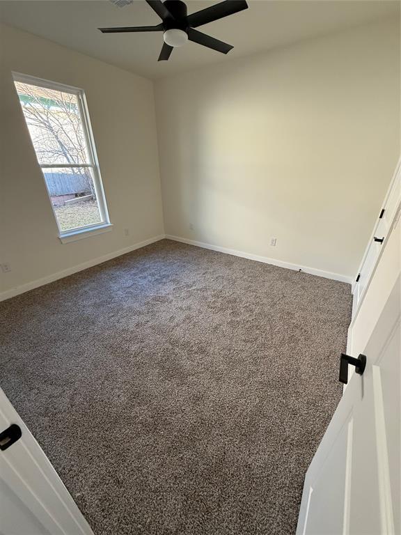 carpeted spare room featuring ceiling fan