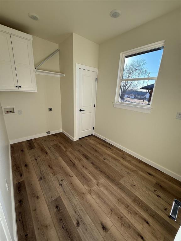 laundry area featuring electric dryer hookup, hookup for a washing machine, dark hardwood / wood-style flooring, and cabinets