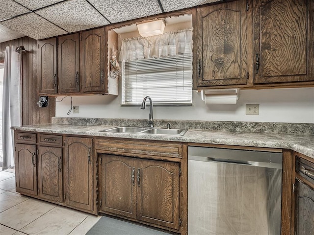 kitchen featuring dishwasher, sink, light tile patterned floors, dark brown cabinets, and a drop ceiling