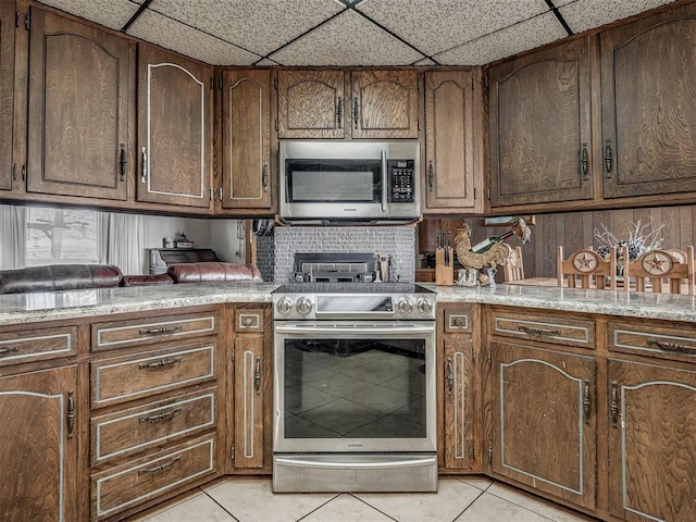 kitchen with light tile patterned floors, a paneled ceiling, and appliances with stainless steel finishes