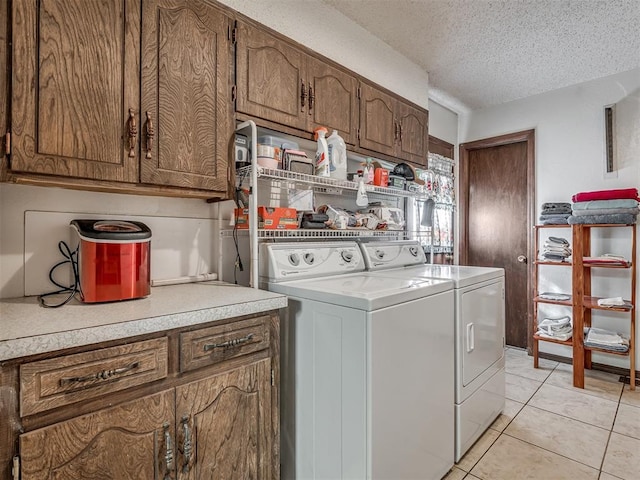 laundry area with cabinets, separate washer and dryer, a textured ceiling, and light tile patterned floors