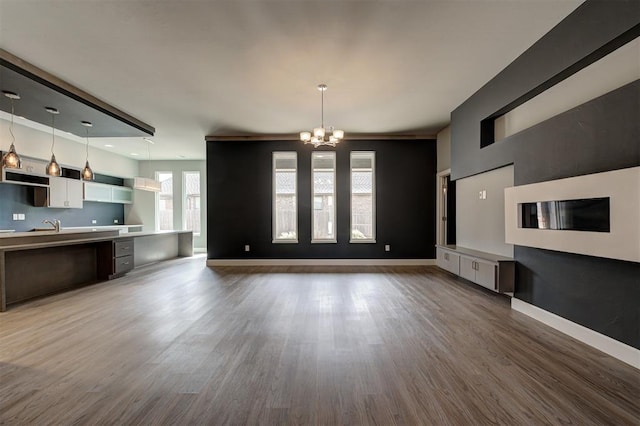 1548 NW 175th Ct, Edmond, OK 73012 - unfurnished living room featuring a chandelier, wood finished floors, and baseboards