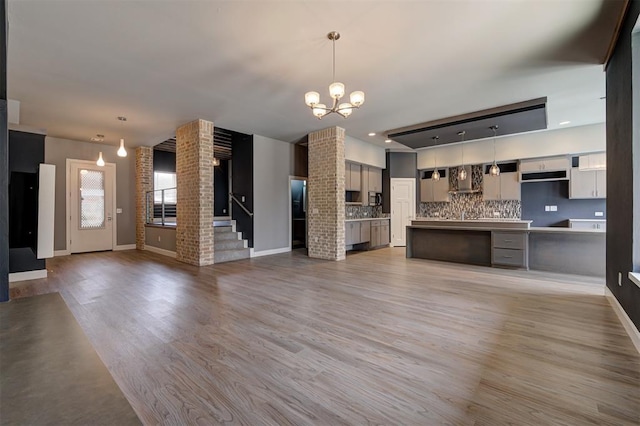 1548 NW 175th Ct, Edmond, OK 73012 - unfurnished living room featuring a chandelier, baseboards, light wood-type flooring, and stairway