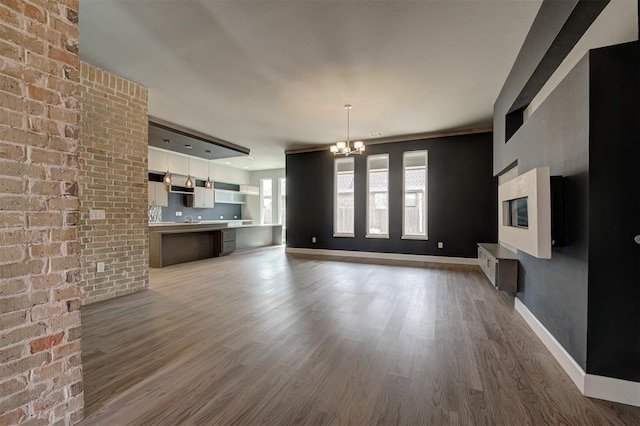 1548 NW 175th Ct, Edmond, OK 73012 - unfurnished living room with a chandelier, wood finished floors, baseboards, and a fireplace