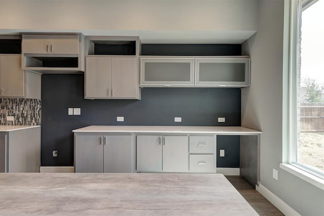 1548 NW 175th Ct, Edmond, OK 73012 - kitchen with backsplash, wood finished floors, glass insert cabinets, baseboards, and light countertops