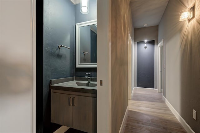 1548 NW 175th Ct, Edmond, OK 73012 - bathroom featuring wood finished floors, vanity, baseboards, and a textured wall