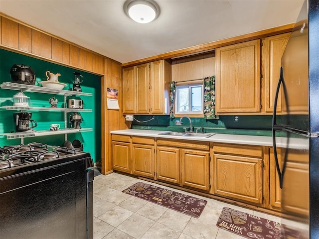 kitchen with sink, light tile patterned floors, wood walls, and black appliances