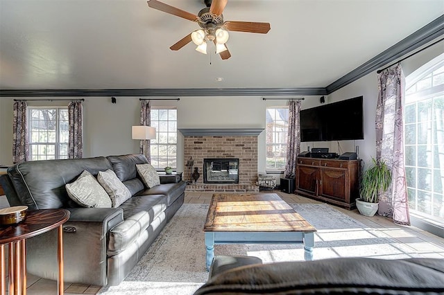 living area featuring a healthy amount of sunlight, a fireplace, crown molding, and a ceiling fan