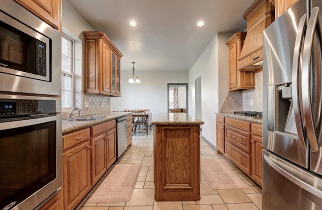 kitchen featuring a sink, appliances with stainless steel finishes, a center island, and a healthy amount of sunlight