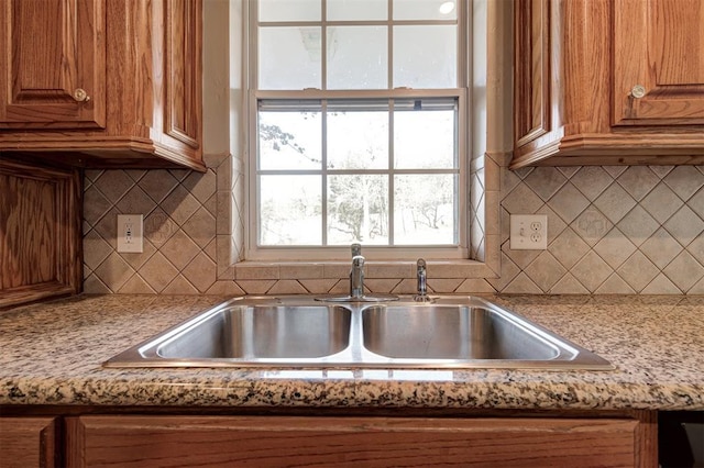 kitchen with decorative backsplash, brown cabinets, and a sink