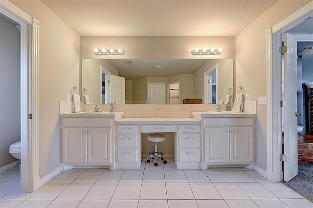 bathroom featuring tile patterned flooring, a sink, toilet, and double vanity