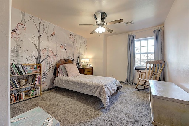 carpeted bedroom featuring visible vents, an accent wall, and a ceiling fan