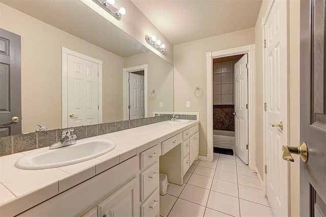 full bath with a sink, double vanity, and tile patterned flooring