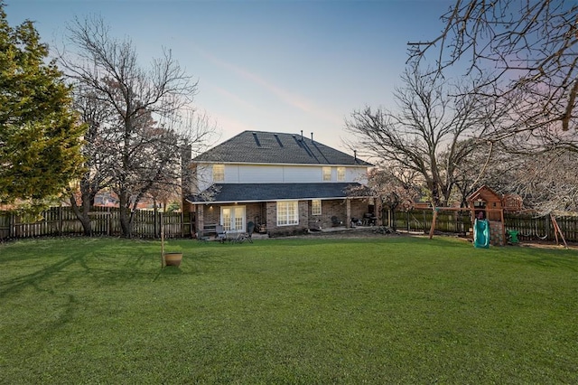 back of property with a yard, a fenced backyard, and a playground