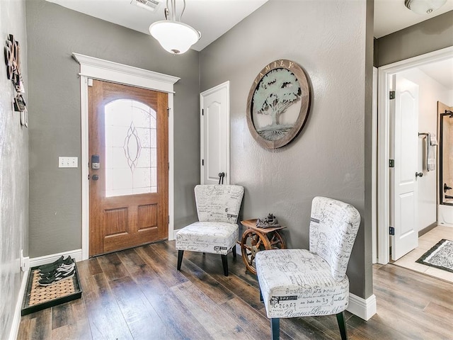 entryway with a textured wall, visible vents, baseboards, and wood finished floors