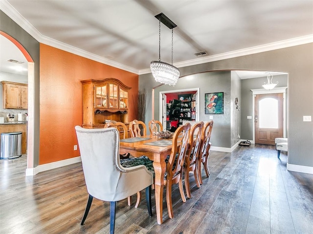 dining area featuring visible vents, arched walkways, dark wood finished floors, and ornamental molding