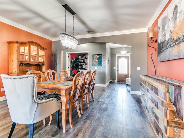 dining room featuring arched walkways, visible vents, dark wood-style flooring, and ornamental molding