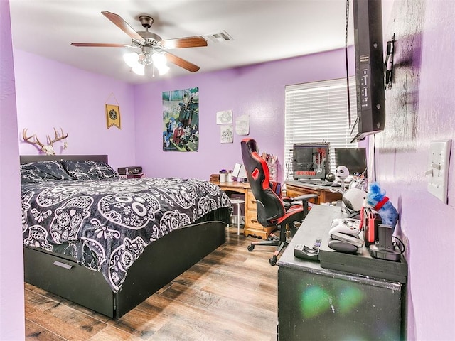 bedroom with wood finished floors, visible vents, and ceiling fan