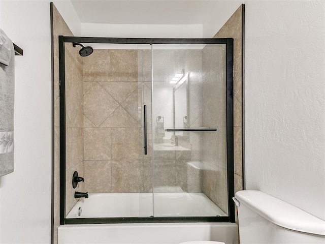 full bath with toilet, a textured wall, and shower / bath combination with glass door