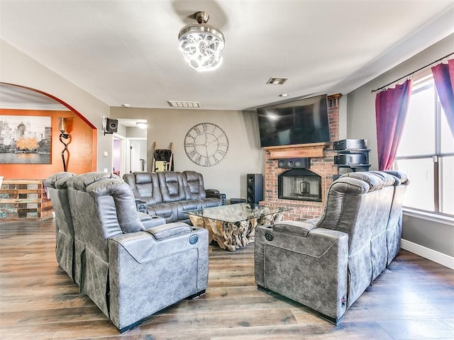 living room featuring visible vents, arched walkways, baseboards, and wood finished floors