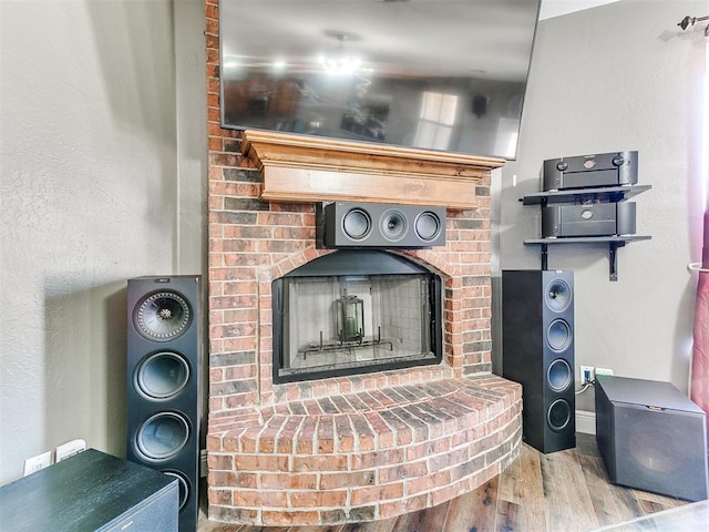 details with a brick fireplace and wood finished floors