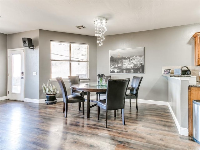 dining room featuring visible vents, baseboards, dark wood-type flooring, and an inviting chandelier