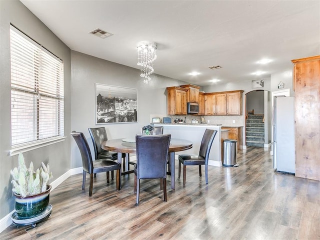 dining space with visible vents, a notable chandelier, and wood finished floors