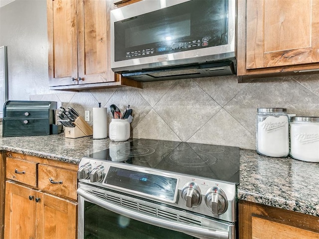 kitchen with tasteful backsplash, appliances with stainless steel finishes, stone countertops, and brown cabinetry