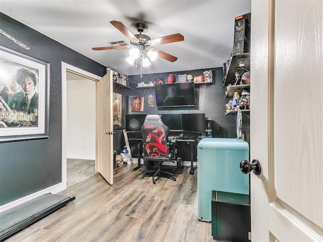 office featuring visible vents, a ceiling fan, wood finished floors, baseboards, and a textured wall