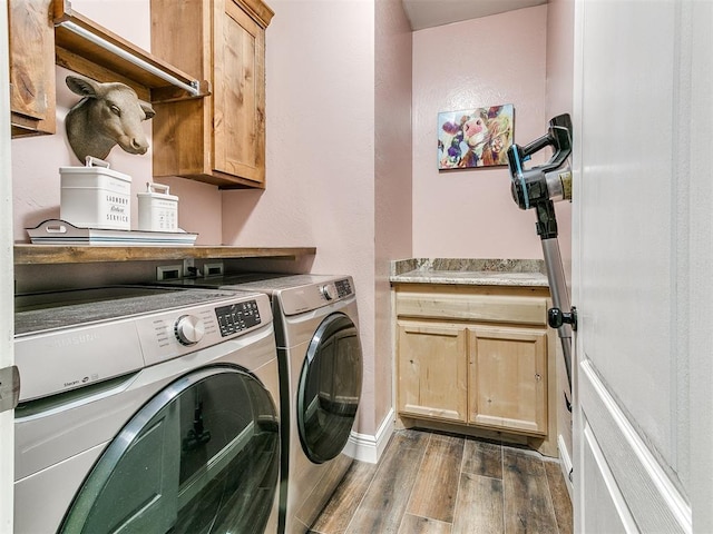 washroom featuring cabinet space, independent washer and dryer, baseboards, and wood finished floors