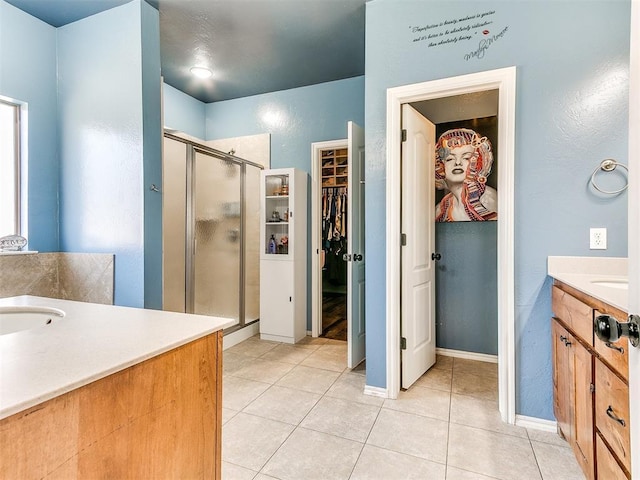 full bathroom featuring vanity, baseboards, tile patterned flooring, a shower stall, and a spacious closet