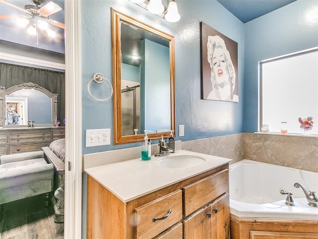 bathroom featuring a jetted tub, a stall shower, a textured wall, vanity, and a ceiling fan