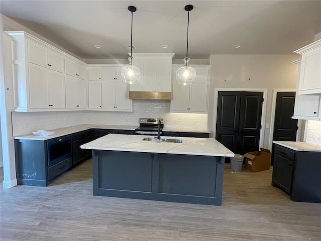 kitchen with an island with sink, sink, pendant lighting, and white cabinets