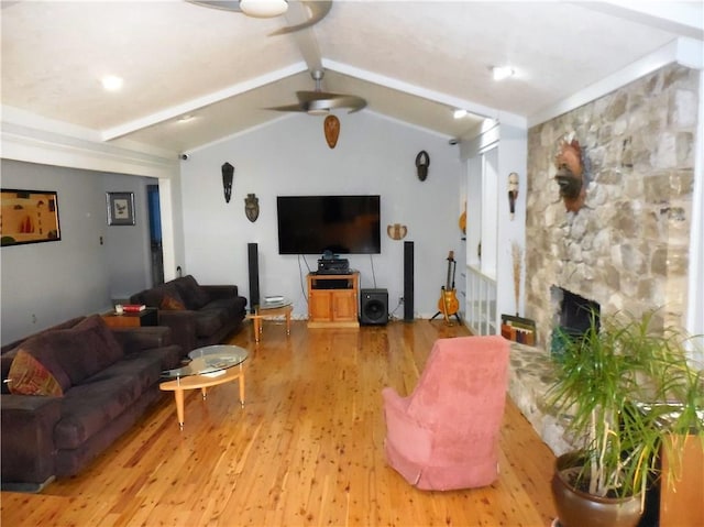 living room with vaulted ceiling with beams, ceiling fan, a fireplace, and light wood-type flooring