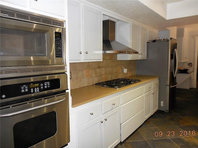 kitchen with stainless steel appliances, white cabinetry, and wall chimney range hood