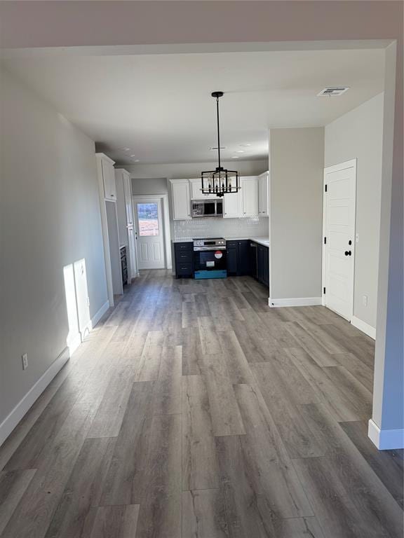 unfurnished living room with wood-type flooring and a notable chandelier