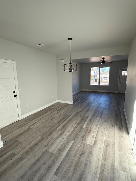 unfurnished dining area with ceiling fan with notable chandelier and hardwood / wood-style floors