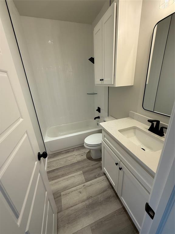 full bathroom featuring shower / bathing tub combination, vanity, hardwood / wood-style flooring, and toilet