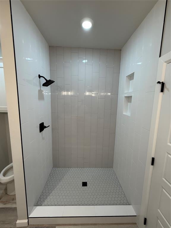 bathroom with tiled shower and toilet