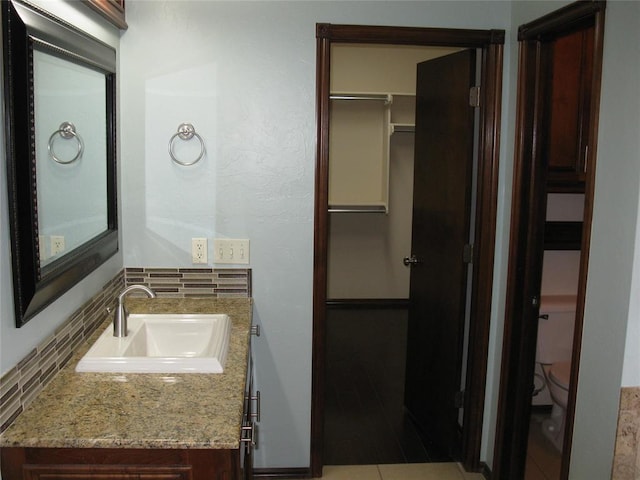 bathroom featuring vanity, toilet, and backsplash