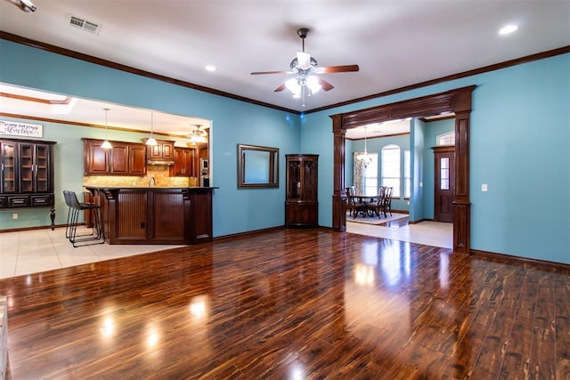 unfurnished living room with ornamental molding, ceiling fan, and light wood-type flooring