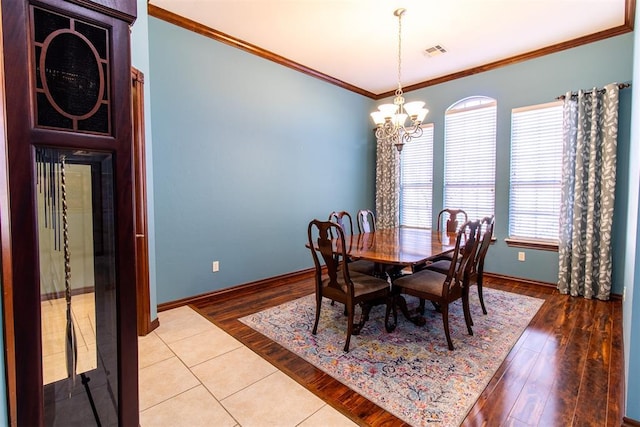 dining space with hardwood / wood-style flooring, ornamental molding, and a notable chandelier