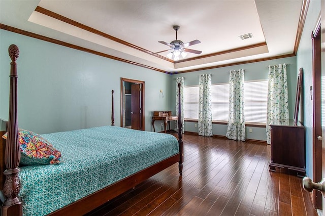 bedroom with crown molding, dark wood-type flooring, ceiling fan, and a tray ceiling