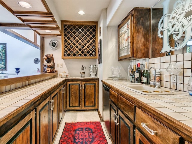 bar with tasteful backsplash, dishwasher, sink, and tile counters