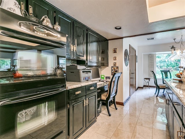 kitchen featuring light stone counters, built in desk, and black double oven