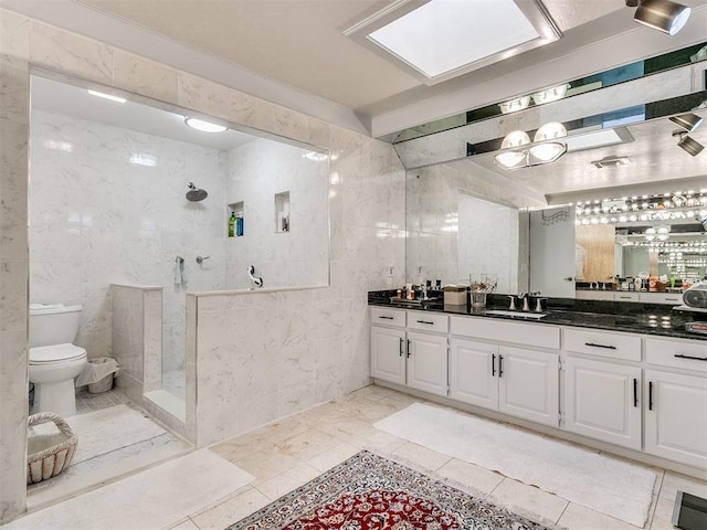 bathroom with toilet, a shower, a skylight, tile walls, and vanity