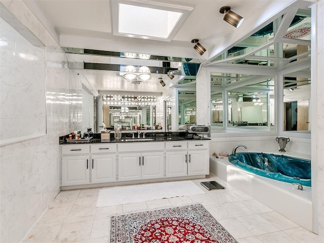 bathroom with vanity, a tub to relax in, a skylight, and tile walls