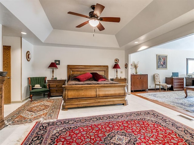 tiled bedroom with a raised ceiling and ceiling fan