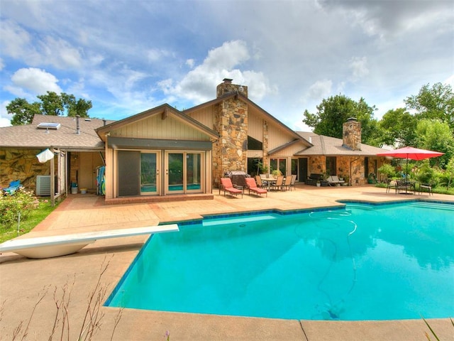 view of pool featuring central AC unit, a patio area, and a diving board